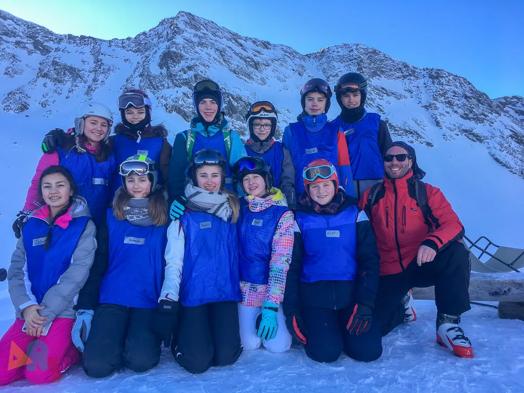 Skigruppe posiert vor der verschneiten Bergkette.